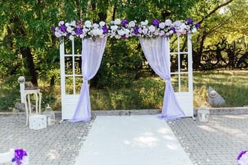 Fototapeta na wymiar wedding decor at a visiting ceremony, a wedding arch of white color with violet flowers