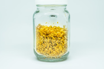 Deep-fried shallots on clear glass jar, isolated on white background.