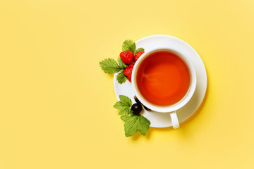 Flat lay composition with a cup of berry tea isolated on a yellow background with place for text.