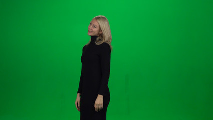 Young female is standing with tender smile. Green screen