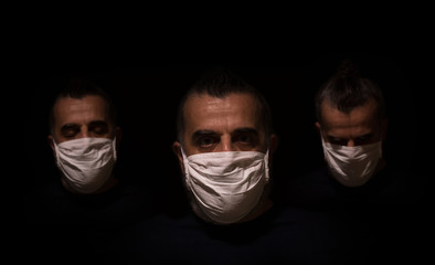 Three male faces in a dark, with different expressions, wearing white medical masks as protection against infection, sad and depressed