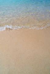 Naklejka na ściany i meble Waves against sandy beach in summer