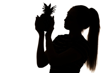 silhouette profile of beautiful woman looking at pineapple and thinking, girl with exotic fruit in hands on white isolated background, concept vitamins and healthy food