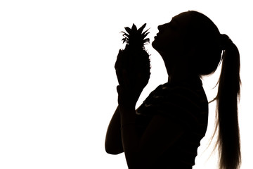 silhouette of woman enjoying smell of pineapple, girl with an exotic fruit near nose on white isolated background, concept vitamins and healthy food