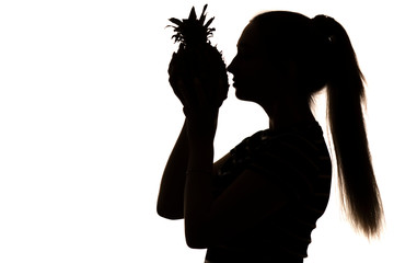 silhouette of woman enjoying smell of pineapple, girl with an exotic fruit near nose on white isolated background, concept vitamins and healthy food