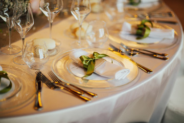 Romantic wedding table arrangement with beige tablecloth and napkins. Wedding table setting close up detail. Restaurant serving on the table close up.