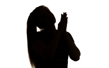 silhouette of a cute girl with hands clasped together begging, young woman with long hair on a white isolated background