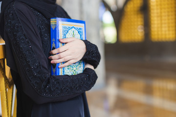 Asian young muslim woman wear hijab black dress holding quran, in mosque.