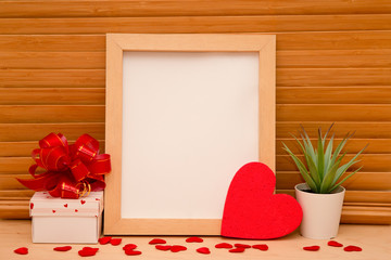 Mother's Day, Women's Day or other suitable holiday card, photo frame with blank space for a text, gift box with red bow and heart on wooden background, stylized image