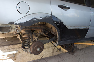 A car without a wheel and brake disc on a repair field accident. car in a garage on earth wheels