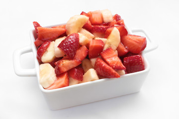 STRAWBERRY AND BANANA FRUIT SALAD IN A BOWL ON WHITE BACKGROUND