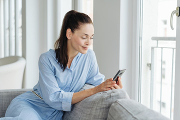 Beautiful woman sitting on a couch with smartphone