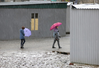 Mom with a daughter in protective masks during quarantine came under rain with hail