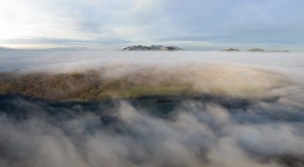 Welsh countryside aerial view with rolling fog, mist and cloud with snow-covered summits