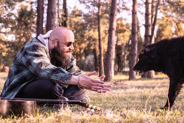 Naklejka na ściany i meble Man hipster playing with dog in nature.