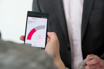 Eine Person hält ein Handy auf dem gerade ein Speedtest läuft