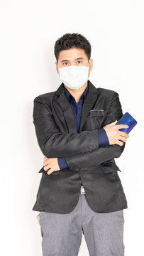 A handsome young man in a black suit wearing a mask and holding the phone with a white background