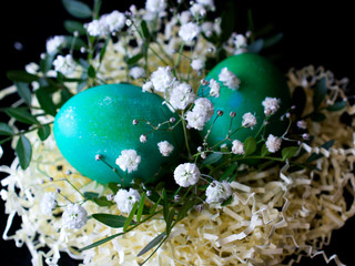 Fototapeta na wymiar green blue Easter eggs in a decorative basket paper nest with flowers and leaves. decorated easter eggs. happy easter greeting card