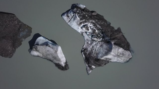 Mud and rock covered glacier ice floating in murky river waters, near Fairbanks, Alaska, slow aerial top down