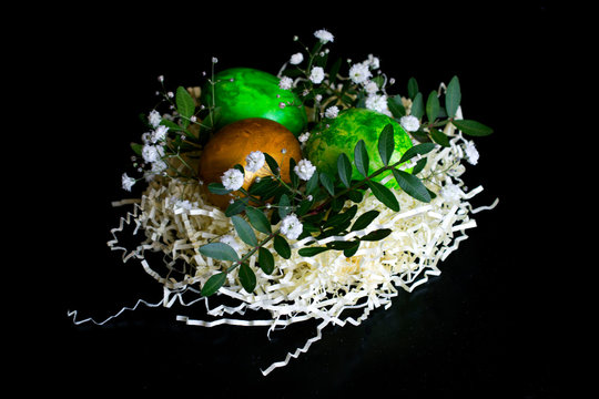 Birds paper nest with eggs decorated with flowers and leaves isolated on black background. happy easter. easter greeting card