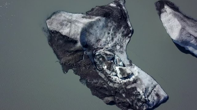 Slow aerial top down orbit of glacier ice floating in murky river waters, near Fairbanks, Alaska,