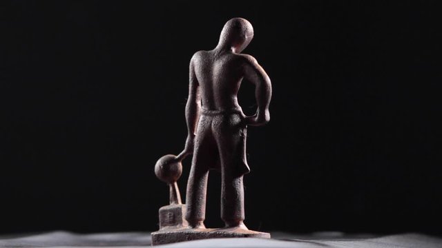 Cast metal statue of a foundry worker. Figure rotates 360-degrees in front of the camera