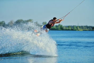 Naklejka premium the guy is riding a wakeboard on the river. Active and Extreme Sports
