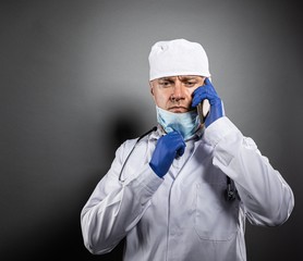 Doctor in white uniform and protective gloves using smart phone