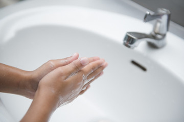 Young woman washing hands with soap over sink in bathroom, closeup