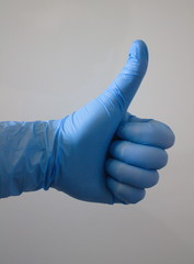 dłoń w niebieskiej rękawiczce jednorazowej pokazująca gest ok - obrazy, fototapety, plakaty