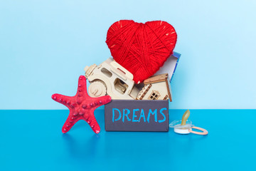 Word Dreams written on gift box, heart, car, house, starfish and pacifier on the blue background.