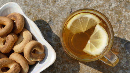 Hot tea in a glass cup. Near the cup lies a plate with bagels.