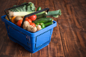 Shopping basket with purchases. Vegetables and fruits on a brown background from boards. Shopping, nutrition and lifestyle
