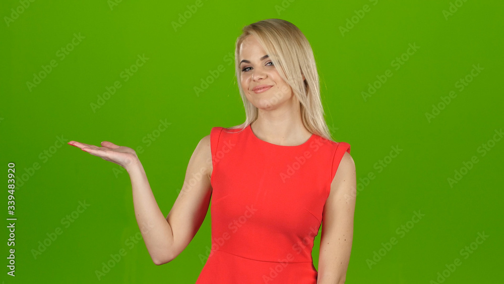 Wall mural lady in red on green screen background shows her hand