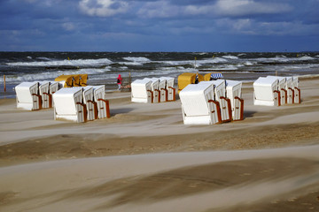 Sztorm na wybrzeżu Morza Bałtyckiego,kosze plażowe stoją na plaży w Kołobrzegu. - obrazy, fototapety, plakaty