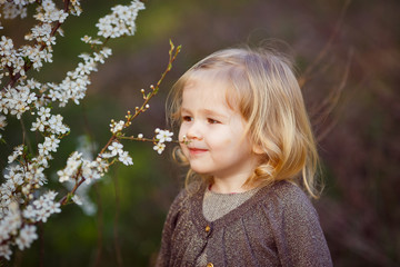 small blond girl in thickets of blooming bushes.