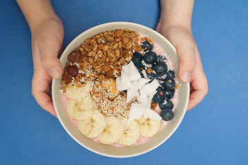 Child holds in hand Handmade Bowl with healthy tasty breakfast