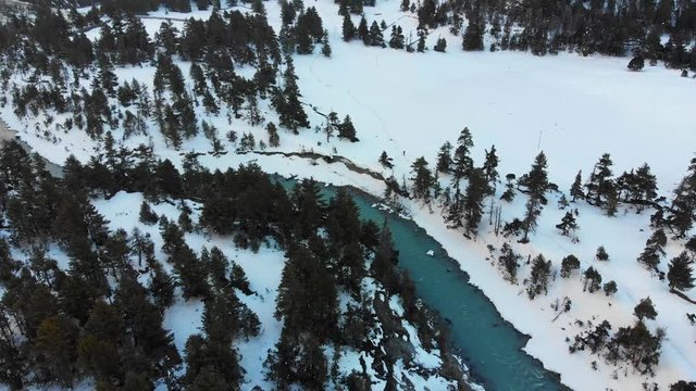 Aerial shot of a landscape with a river flowing in a snow-covered area in Alpine Region Manang Valley, Nepal.