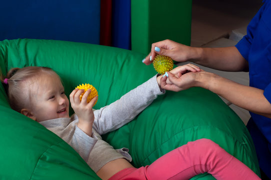 sensory therapist massaging little girl patient with a little ribbed ball