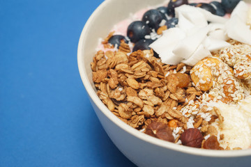 Handmade Bowl healthy tasty breakfast of yogurt, smoothie with granola, nuts, bananas and berries