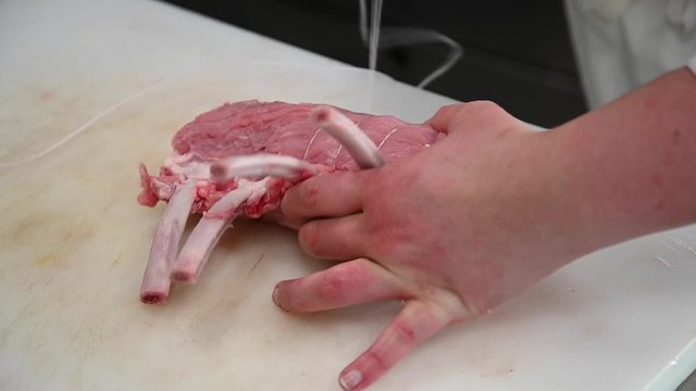 main mettant une ficelle &agrave; une viande