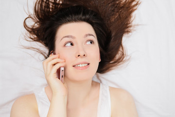 Girl lying on the bed and talking on the phone.