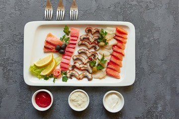 White rectangular plate with smoked and salted fish delicacies