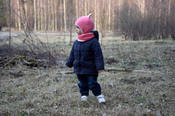 Little girl walks on a gray spring field in countryside