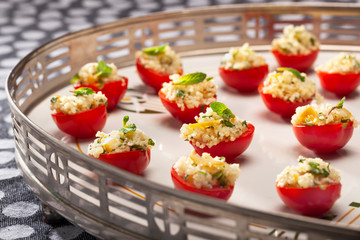 Selective focus on healthy red tomatoes filled with couscous, lemon and a mint leaves on top