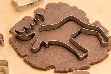 A moose-shaped cookie mold lies on a small rolled piece of brown dough