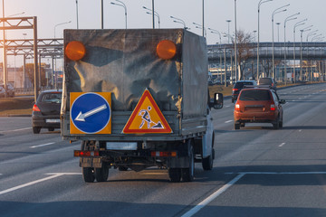 A small truck with road equipment and tokens for other drivers drives along the highway.