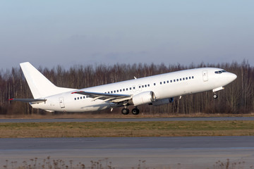 Fototapeta na wymiar White passenger commercial plane takes off from runway side view.