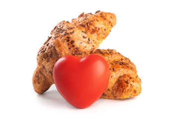 Photo of fresh golden croissants covered sunflower seeds and sesame isolated on white background with red heart.