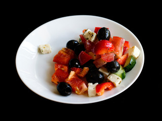 fresh greek salad in white plate on black table. vegetable salad with feta cheese. healthy food.